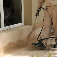 General pest control technician spraying exterior perimeter around a home in Tallahassee, FL