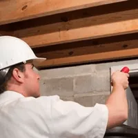 Termite inspection technician checking a basement wall and framing for termite activity in Tallahassee, FL